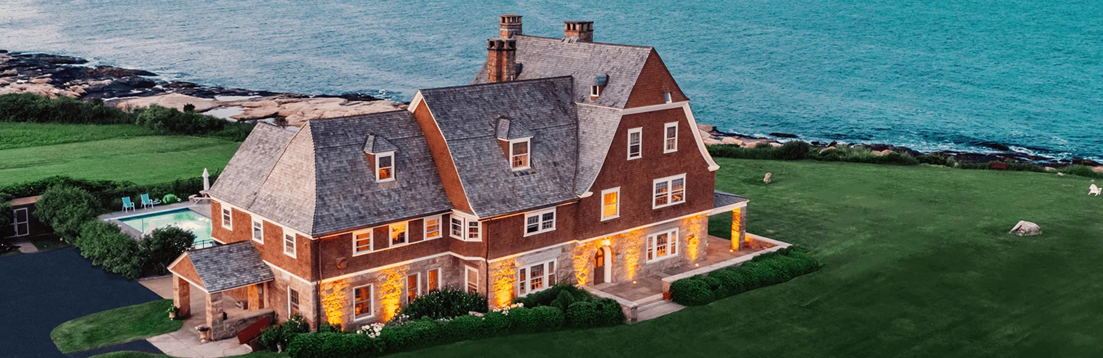 Complete coastal house with a cedar roof, shingle siding, lawns, and an ocean backdrop