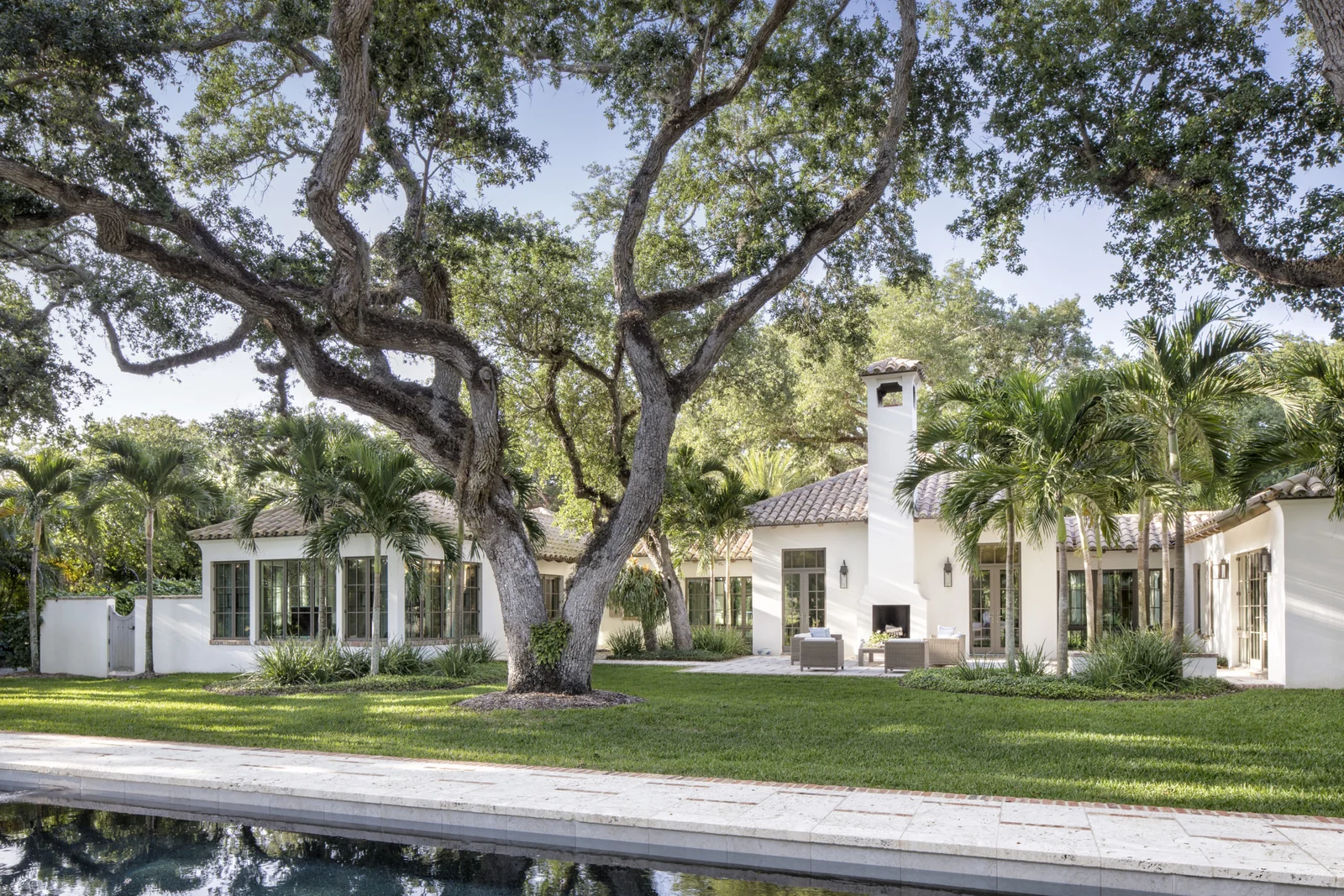 White Spanish Colonial home in Vero Beach with Ludowici clay roof tiles and mature oak trees