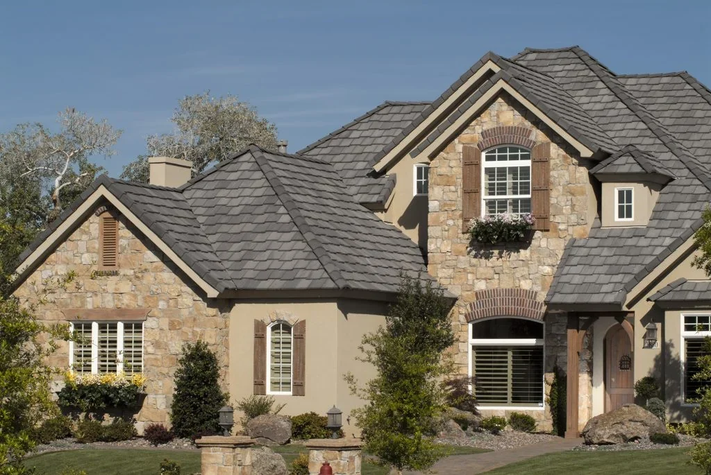 Stone-front home with gray Eagle concrete roof tiles, windows, and a landscaped entry