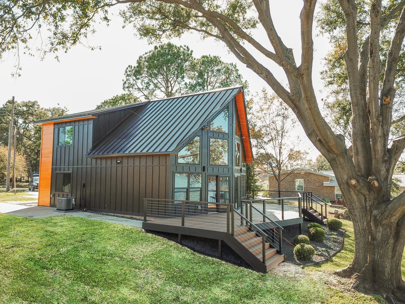 Contemporary lake house with a dark standing-seam metal roof, wood accents, and a deck